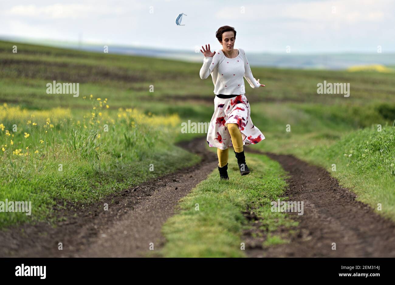 Woman taking off and throw away used medical face protective mask in the outdoors. End of pandemic quarantine, coronavirus Covid-19 concept Stock Photo
