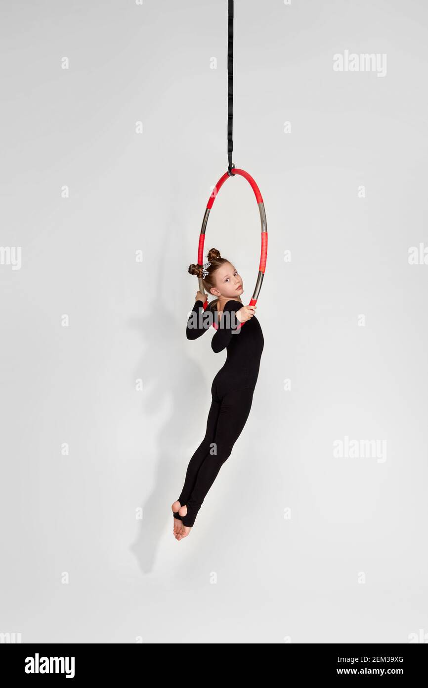 Little acrobat girl shows an acrobatic performance on an aerial hoop Stock Photo