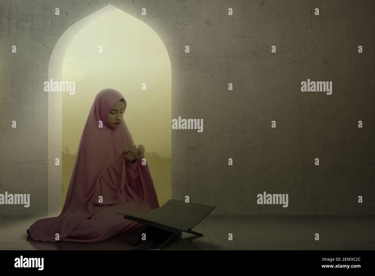 Asian Muslim woman in a veil sitting while raised hands and praying in ...