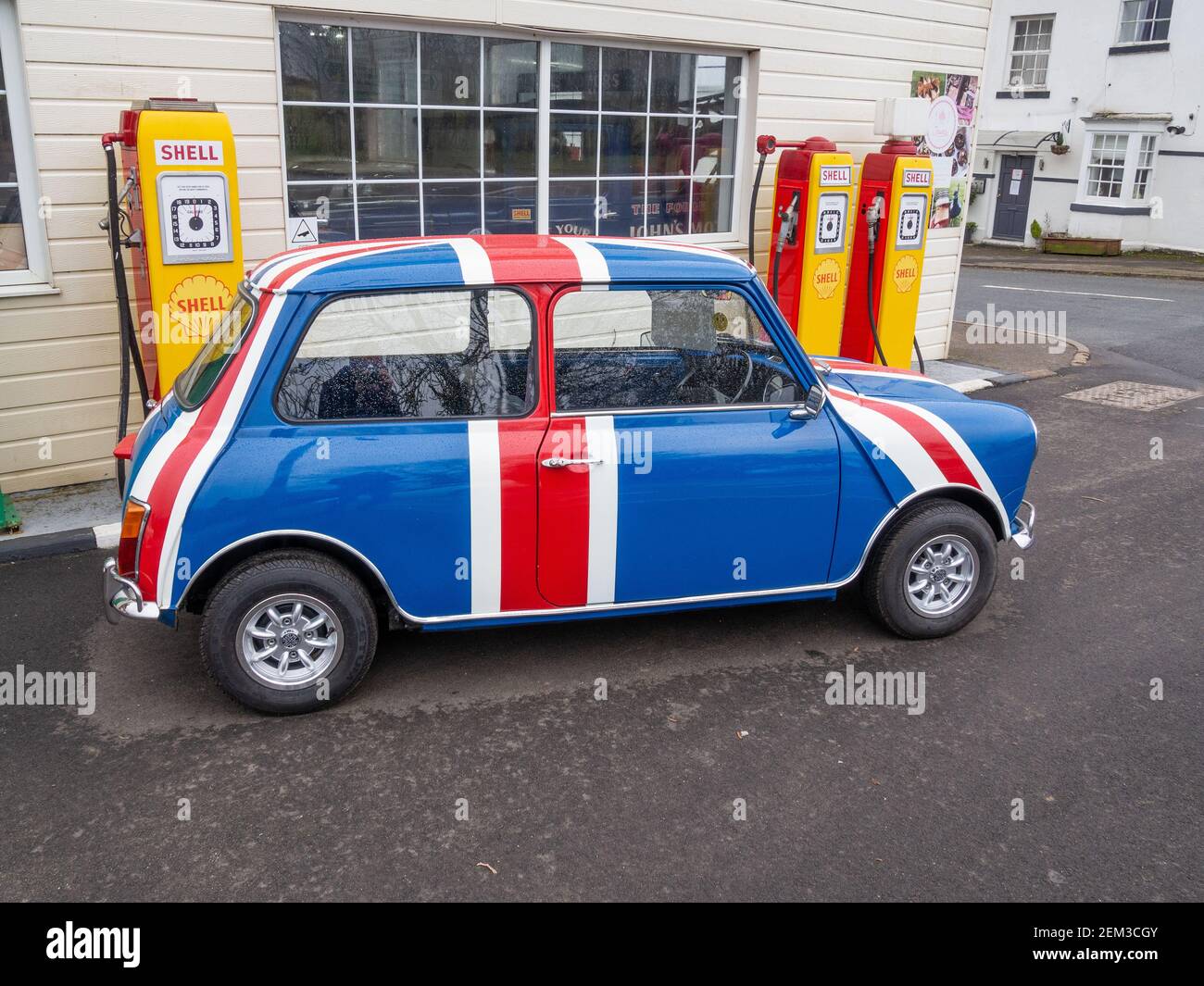 Vintage Austin Mini in Union Jack colours in front of old style Shell petrol pumps, Patishall, Northamptonshire, UK Stock Photo