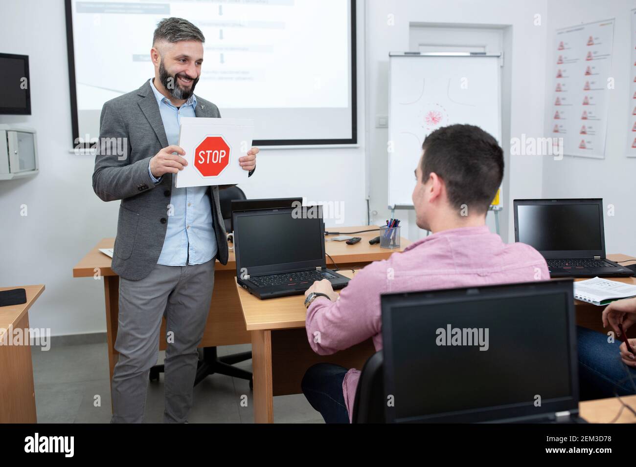 Driving instructor holding an image of a STOP traffic sign and showing ...