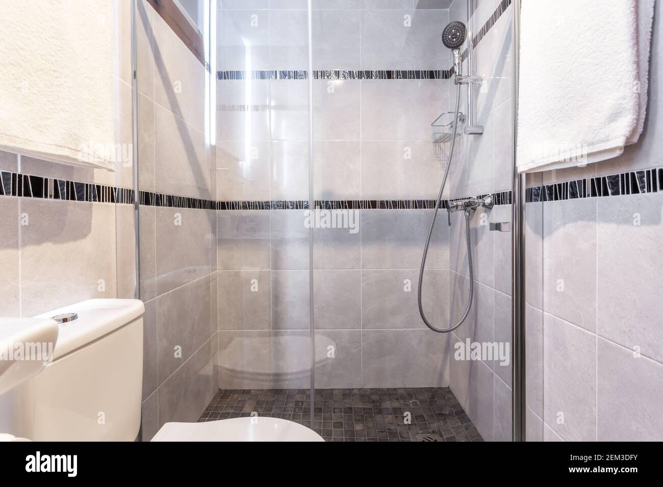 Shot of modern bathroom with a clean shower set up, towels hanging on the walls and a gimplse of the toilet seat. Stock Photo