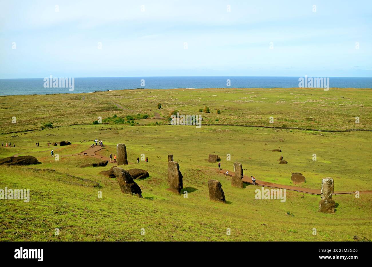 Group of Visitors visiting the site of abandoned unfinished giant Moai statues at Rano Raraku volcano with Pacific ocean in backdrop, Easter Island, C Stock Photo