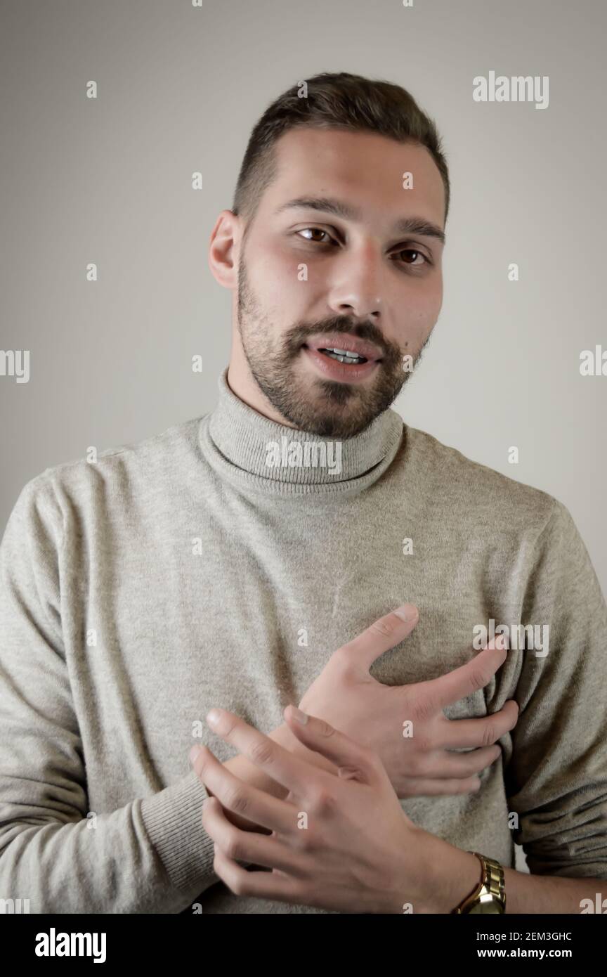 Portrait of a young man with a short beard with with his hand over his heart as a sign of sincerity Stock Photo