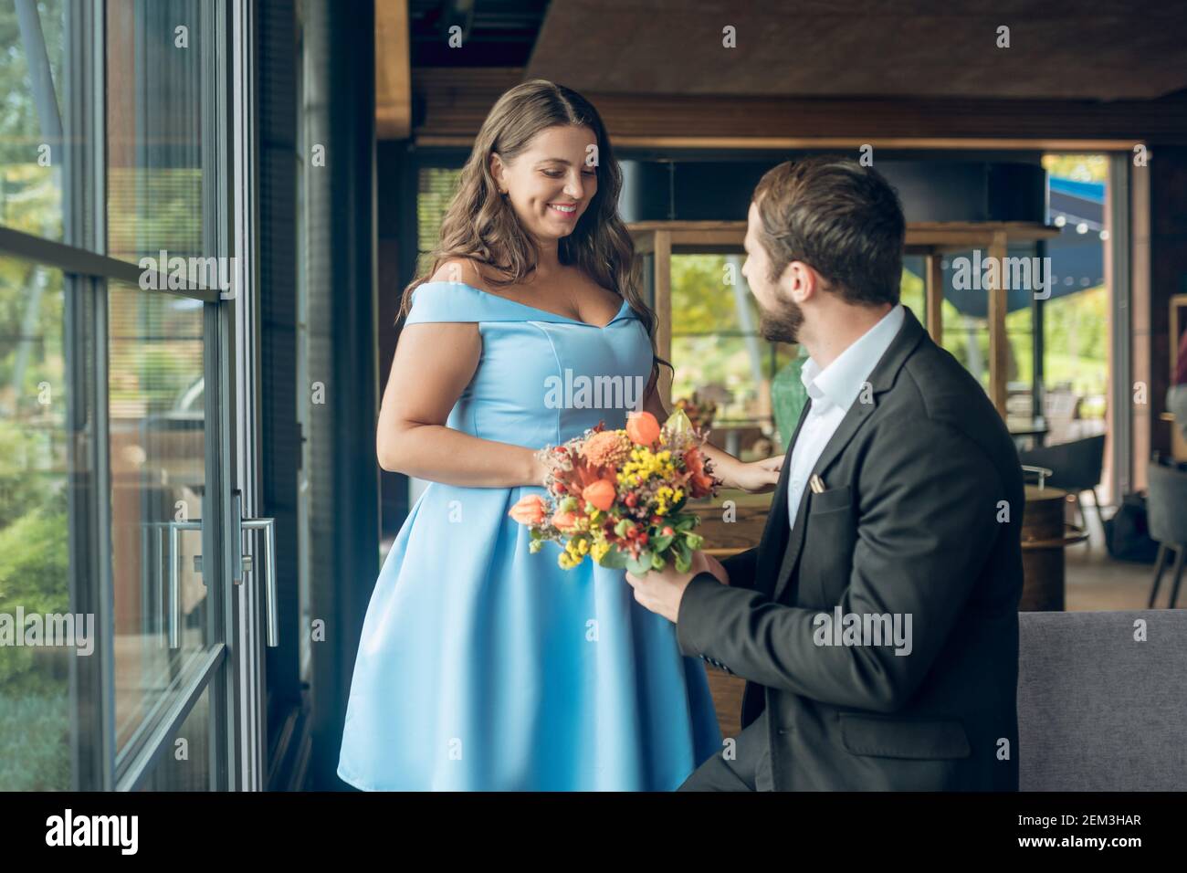 Beautiful smiling woman and man holding flowers Stock Photo