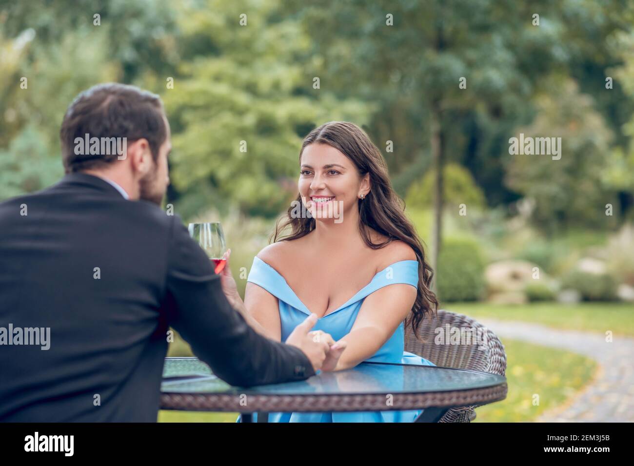 Woman and man touching hand sitting in outdoor cafe Stock Photo
