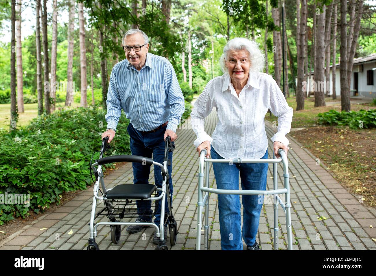 Elderly couple in the park strolling with walkers, senior citizen concept Stock Photo