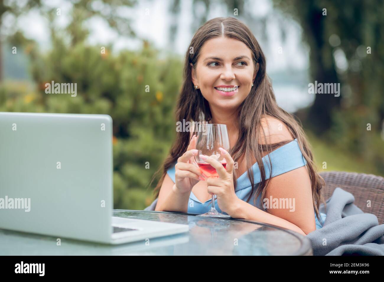 Woman with glass near laptop in dreamy mood Stock Photo