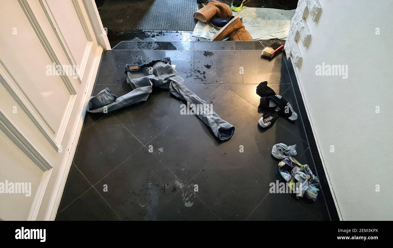 boy took off his wet clothes and left them carelessly in the hallway , Germany Stock Photo