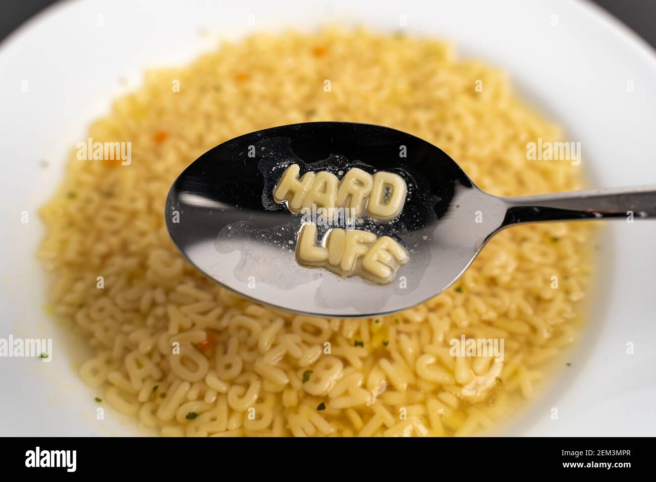 Alphabet soup letters with Hard Life on the spoon, instant easy fast food because of poverty Stock Photo