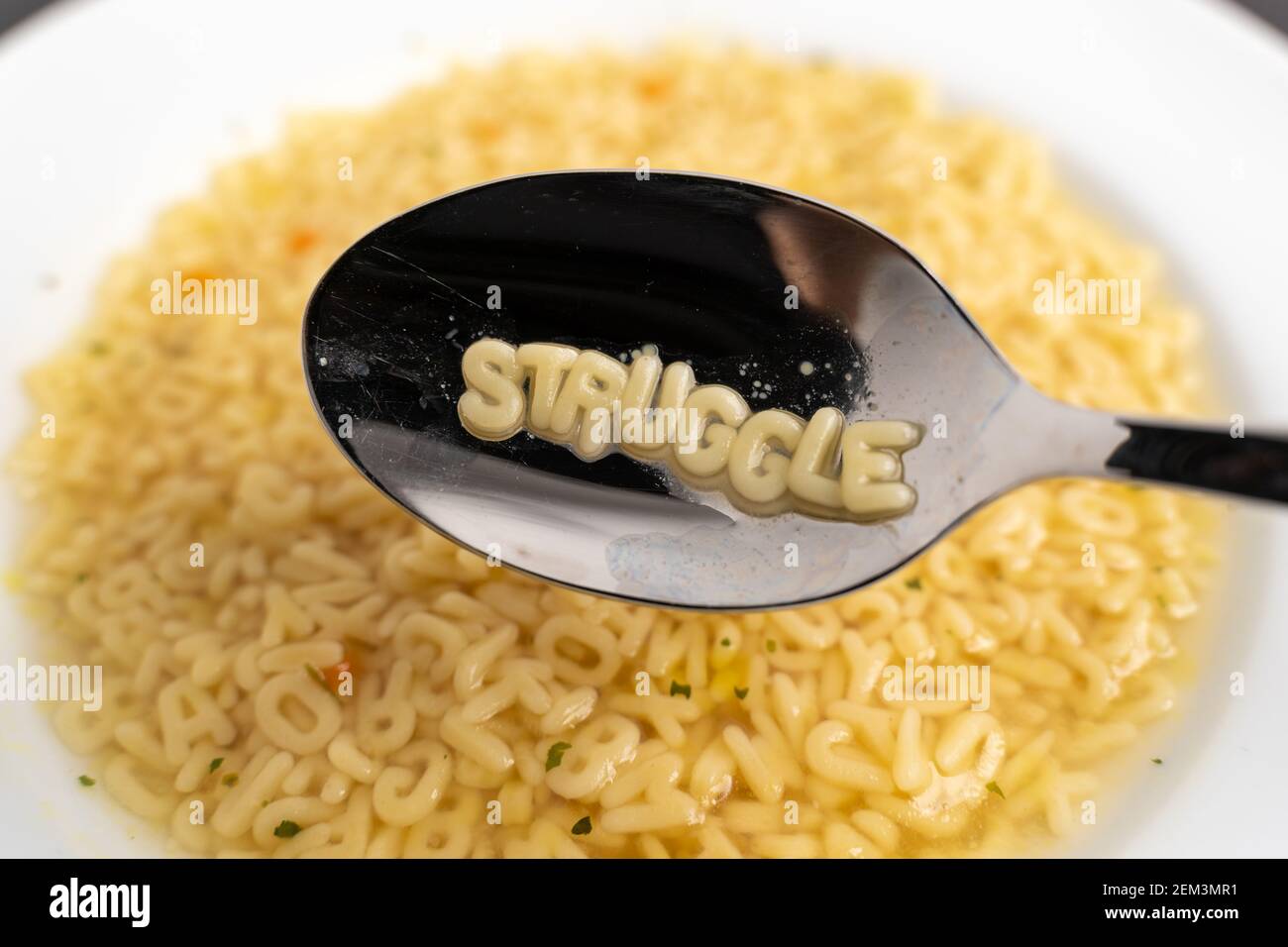 Alphabet soup letters with Struggle on the spoon, instant easy fast food because of poverty Stock Photo