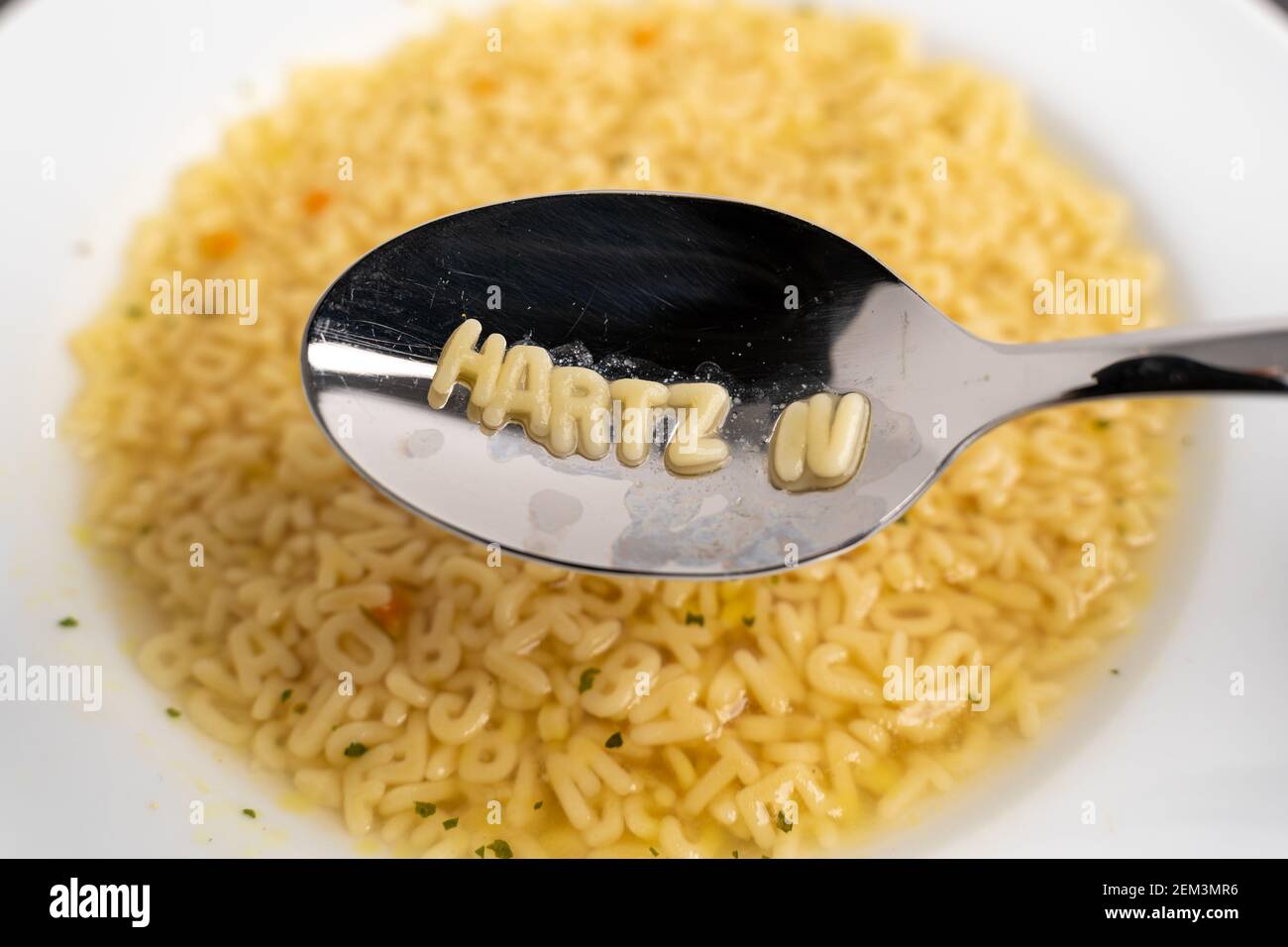 Alphabet soup letters with Hartz IV on the spoon, instant easy fast food because of poverty Stock Photo