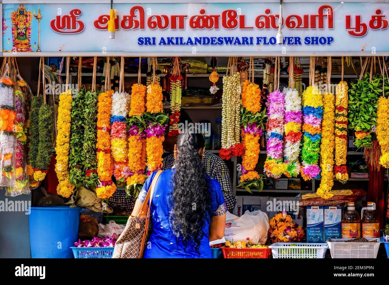 Singapore, Singapore - December 5, 2015. A woman stands at a small flower shop in Little India, which sells fresh floral garlands used in Hinduism. Stock Photo