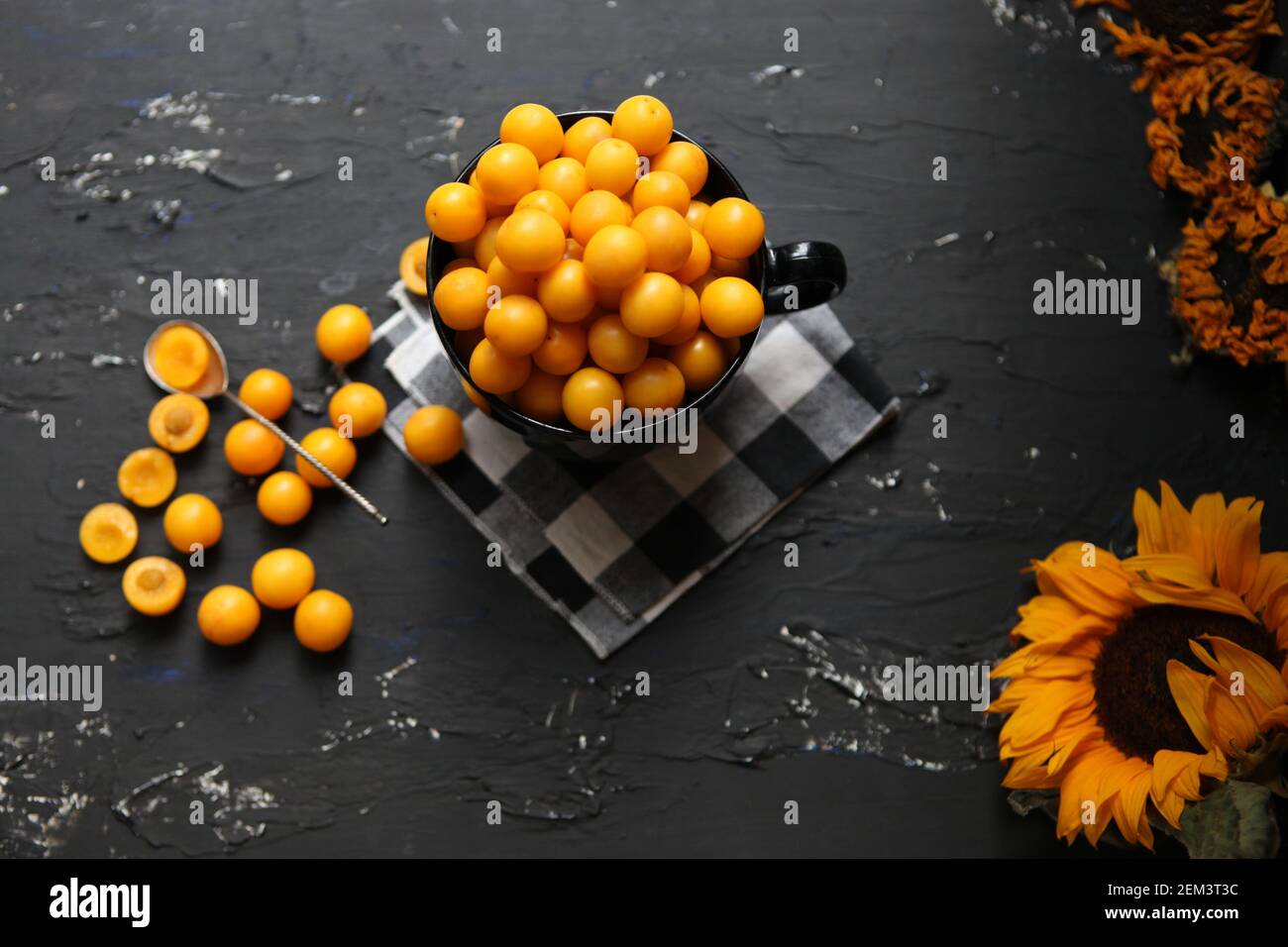 Yellow plums on the black background. Ingredients for a jam. Food photography. Yellow sunflower, top view. Autumn Concept, Stock Photo