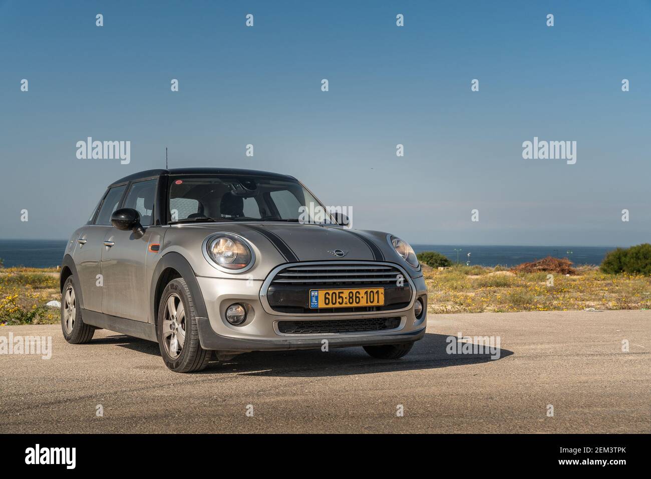 Grey Mini cooper with a sea and blue sky background Stock Photo