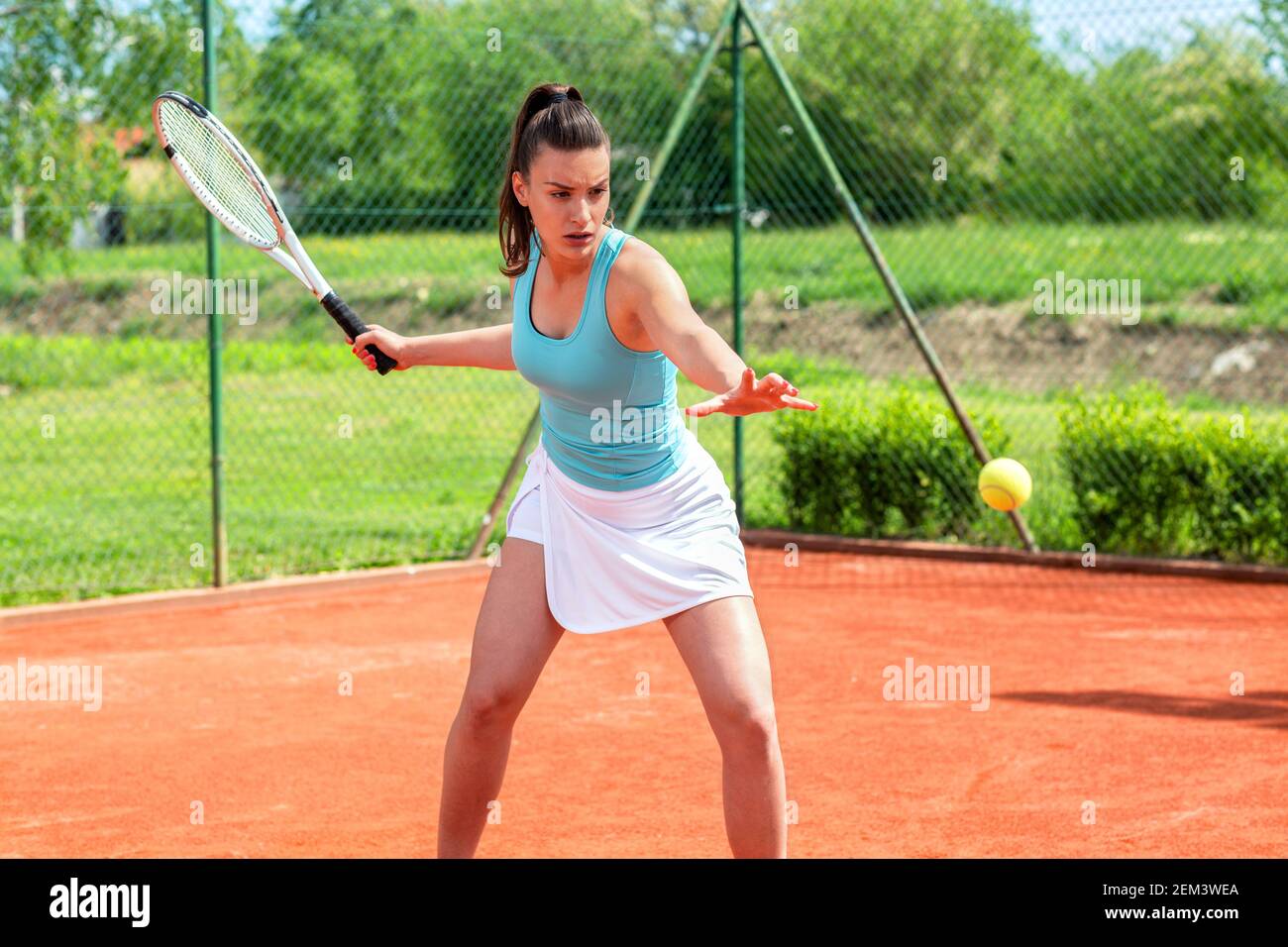 Beautiful girl fully concentrated to hit a tennis ball with a forehand  stroke Stock Photo - Alamy