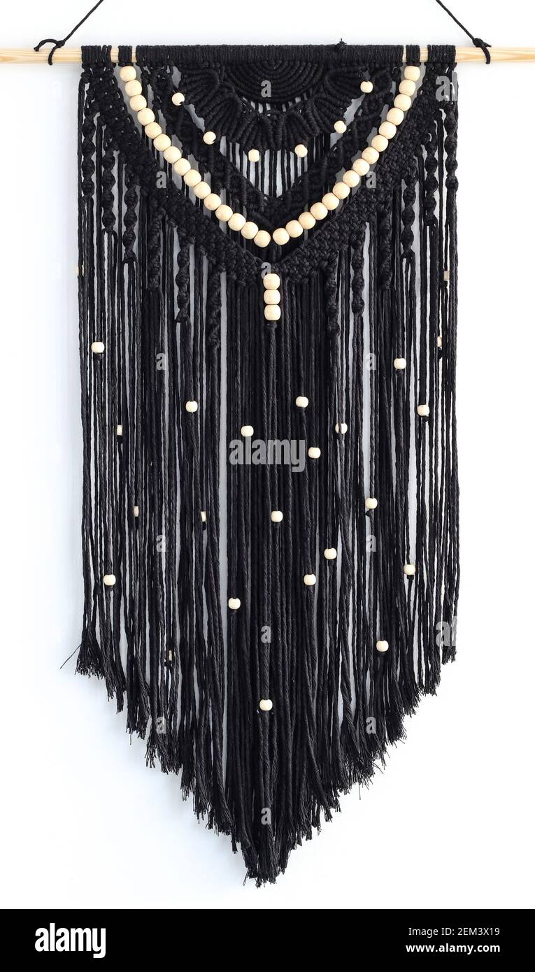 Hand woven black macrame with white beads hanging on wall Stock