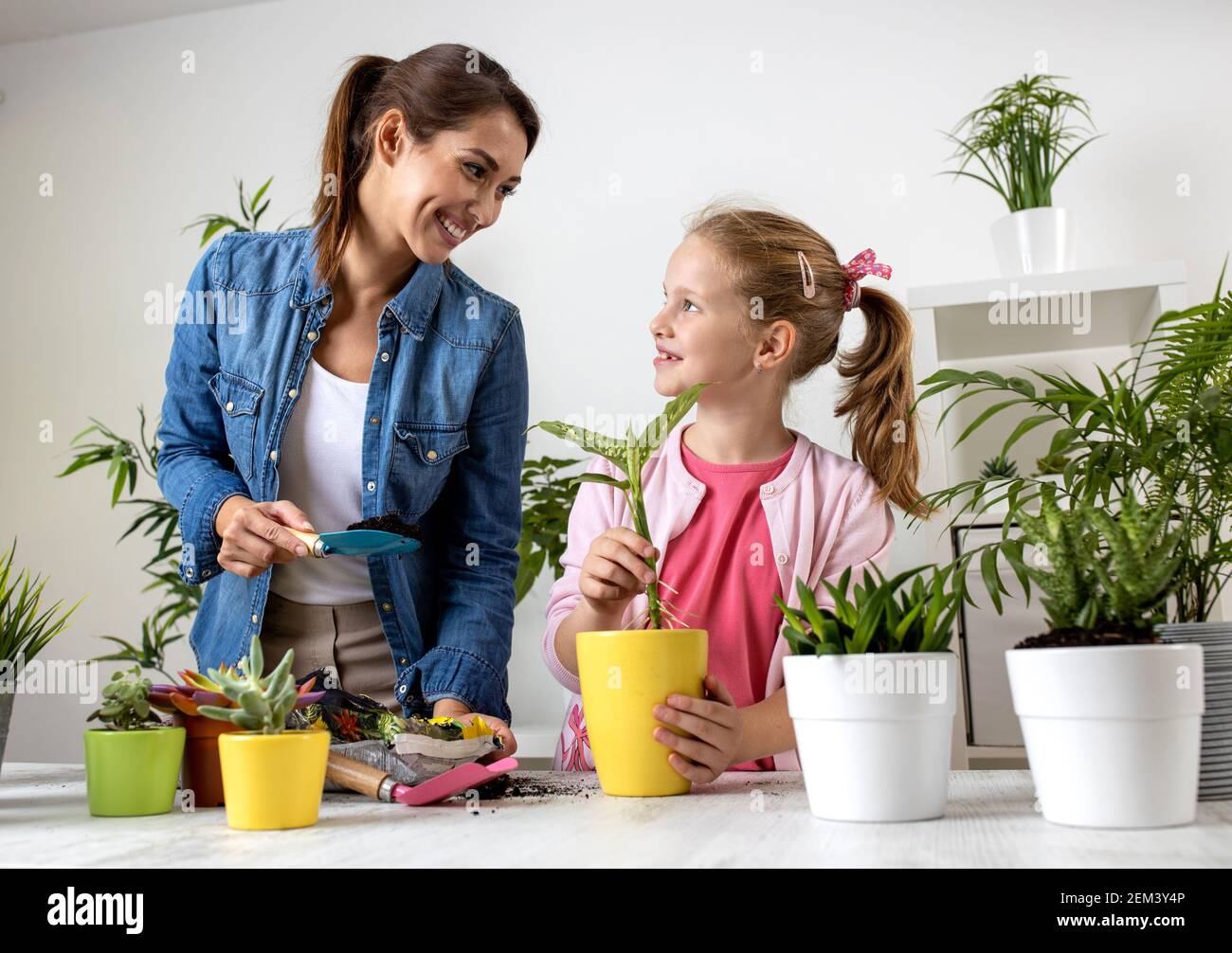 Mom teaching her daughter about replanting techniques, potting