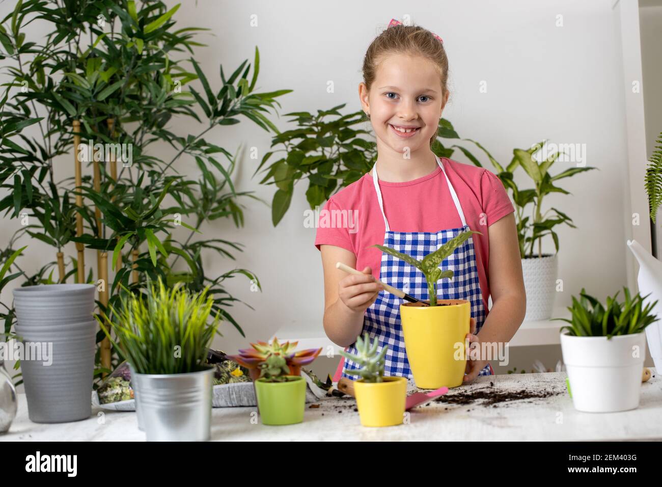 Young girl with a sincere smile on her face having fun with a plant in ...
