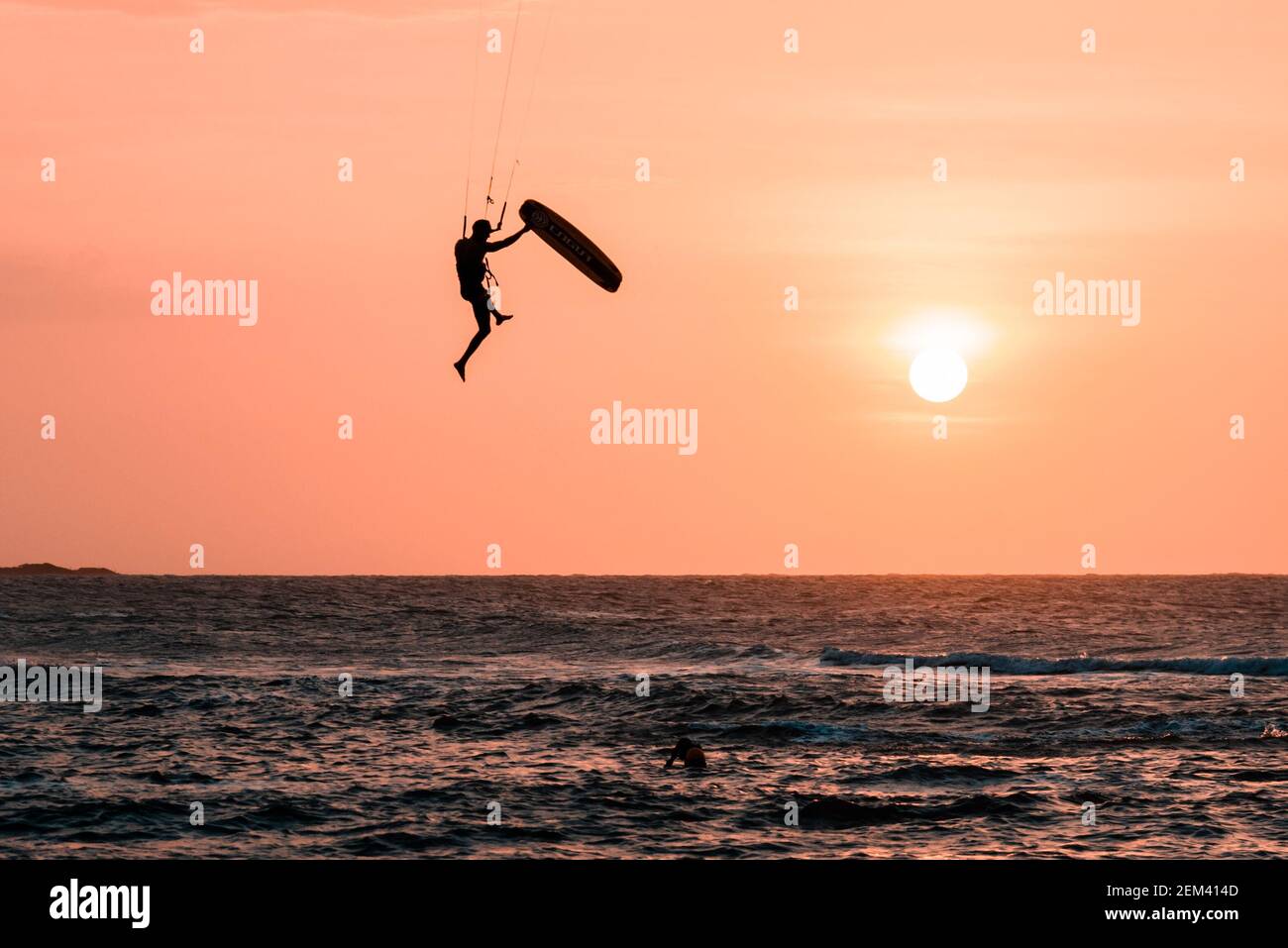 Man kiteboarder athlete silhouette while jumping and kitesurfing at sunset. Landscape