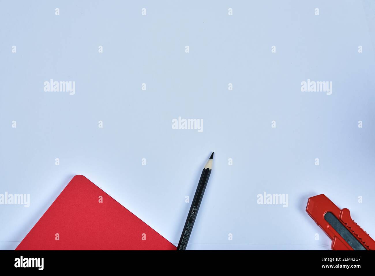 Notebook, utility knife and pencil on blue background Stock Photo