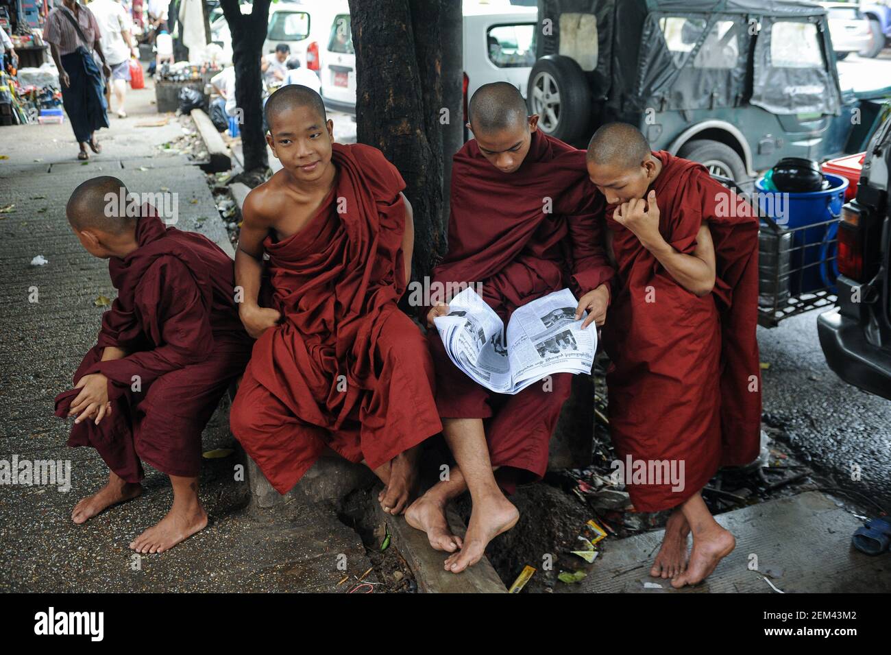 27.07.2013, Yangon, Myanmar, Asia - A group of Buddhist monks in their saffron robes read a newspaper in downtown Yangon, the former capital city. Stock Photo