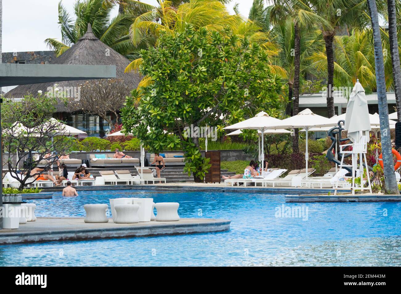 view onto a hotel resort swimming pool in Mauritius with people sunbathing concept tropical island holiday Stock Photo