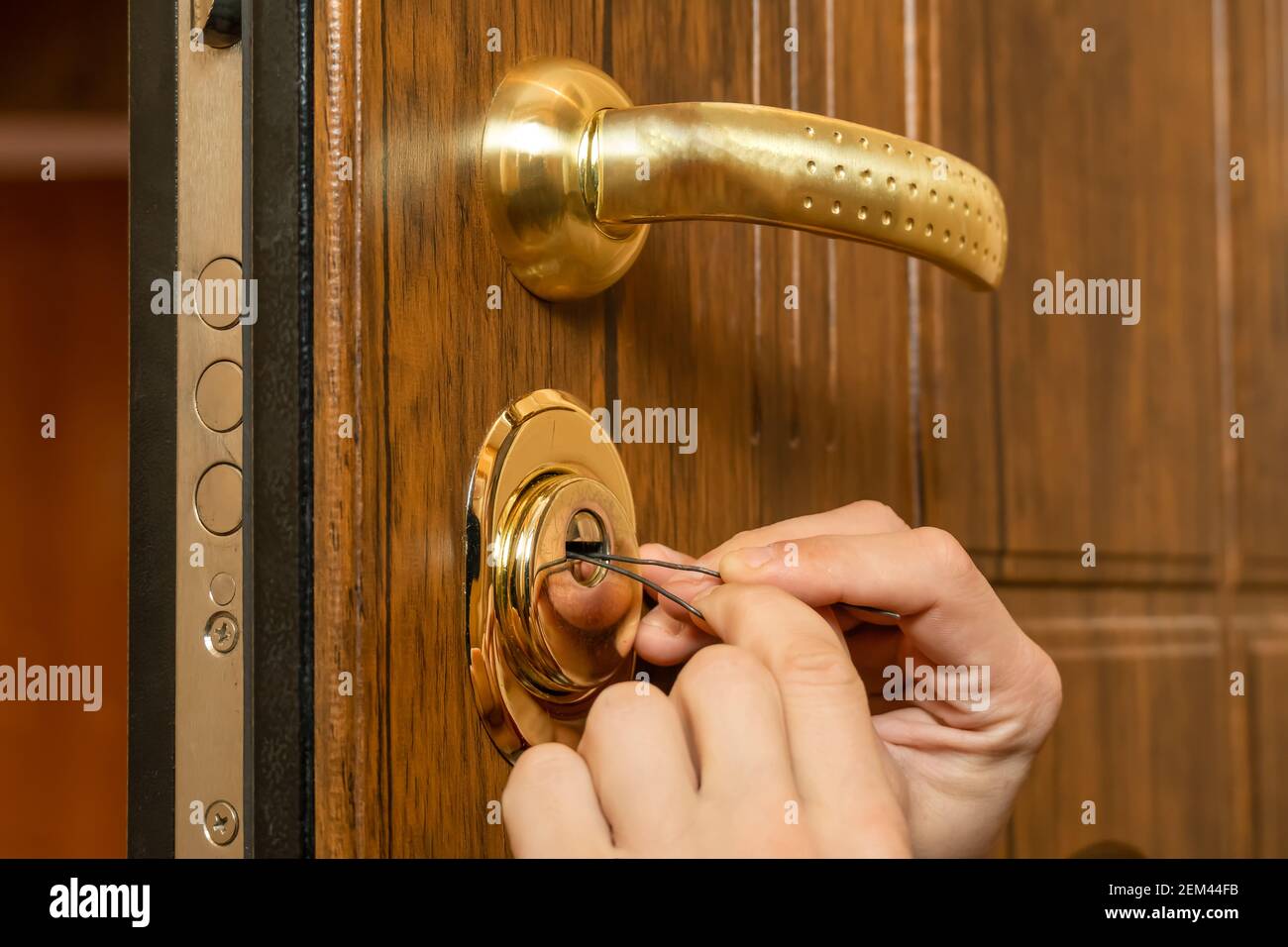 https://c8.alamy.com/comp/2EM44FB/male-hands-break-open-a-brown-front-door-with-a-lock-pick-close-up-2EM44FB.jpg