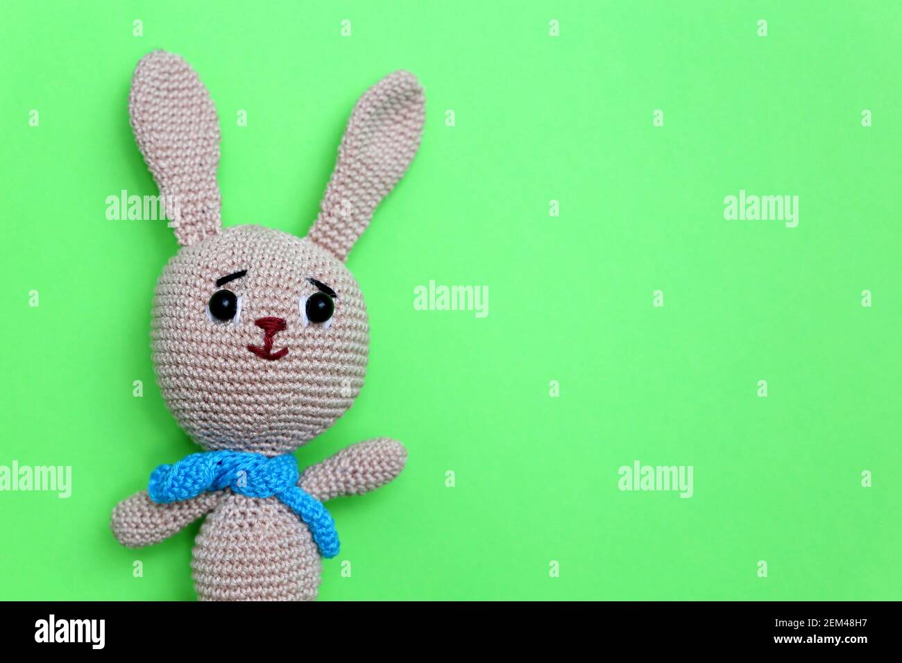 Easter Bunny on light green background. Greeting card with knitted toy rabbit with free copy space Stock Photo