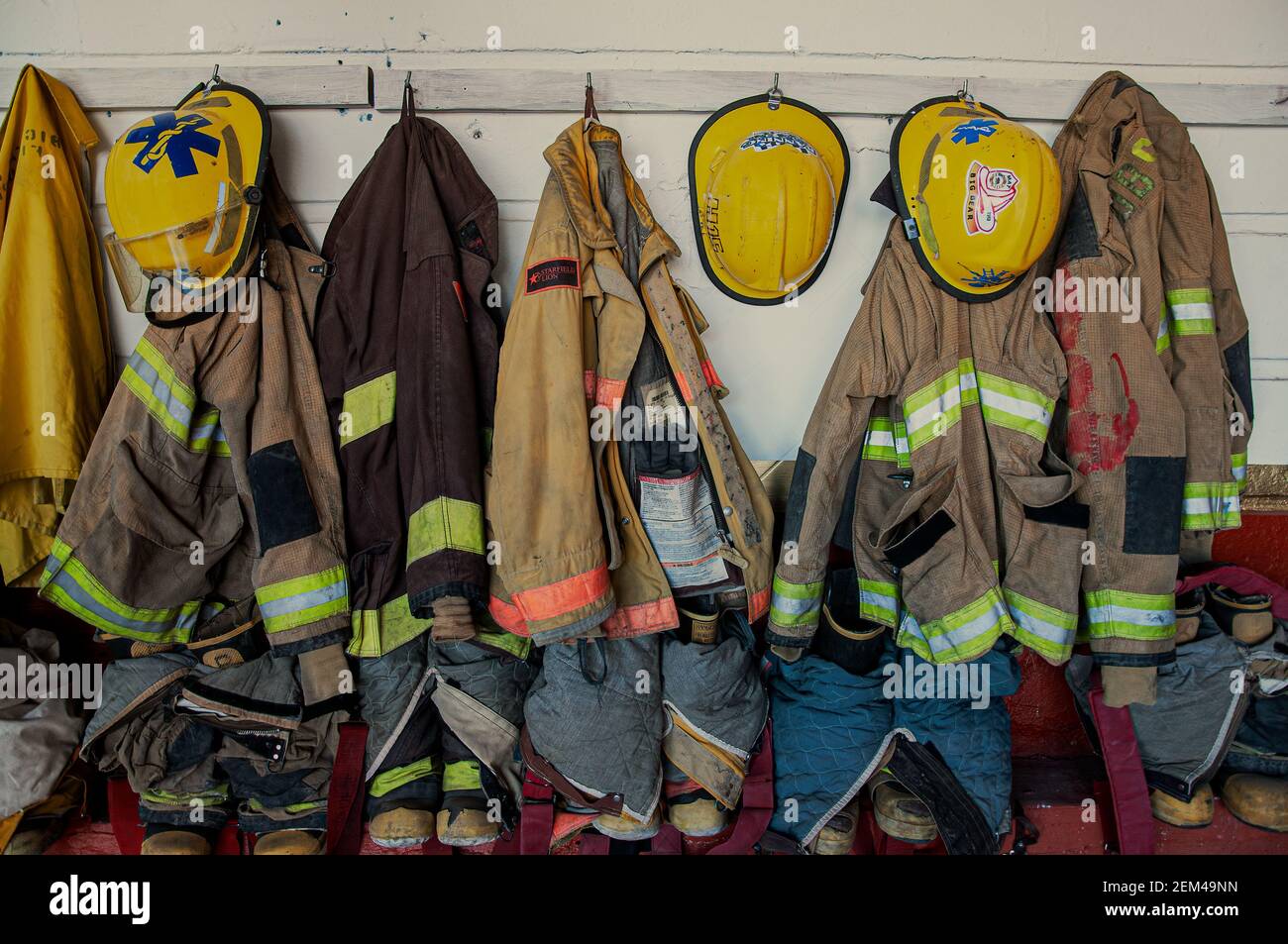 Firefighters’ gear hanging on hooks, arranged and ready to go. Stock Photo