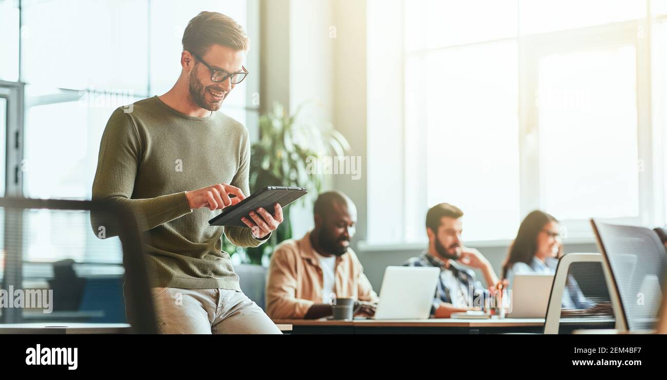 Joyous young gentleman using his tablet for work Stock Photo