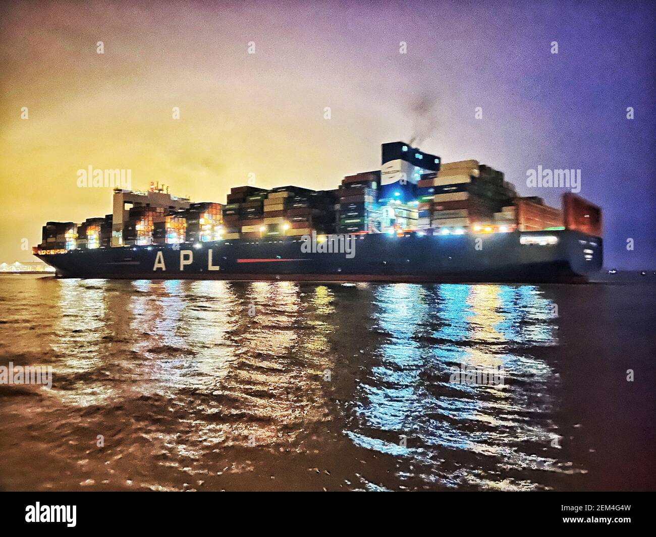 01 January 2021, Hamburg: The lights of the container ship of the shipping company American President Lines Ltd.(APL) passing Blankenese are reflected by the water surface of the Elbe in the early evening. Photo: Soeren Stache/dpa-Zentralbild/ZB Stock Photo