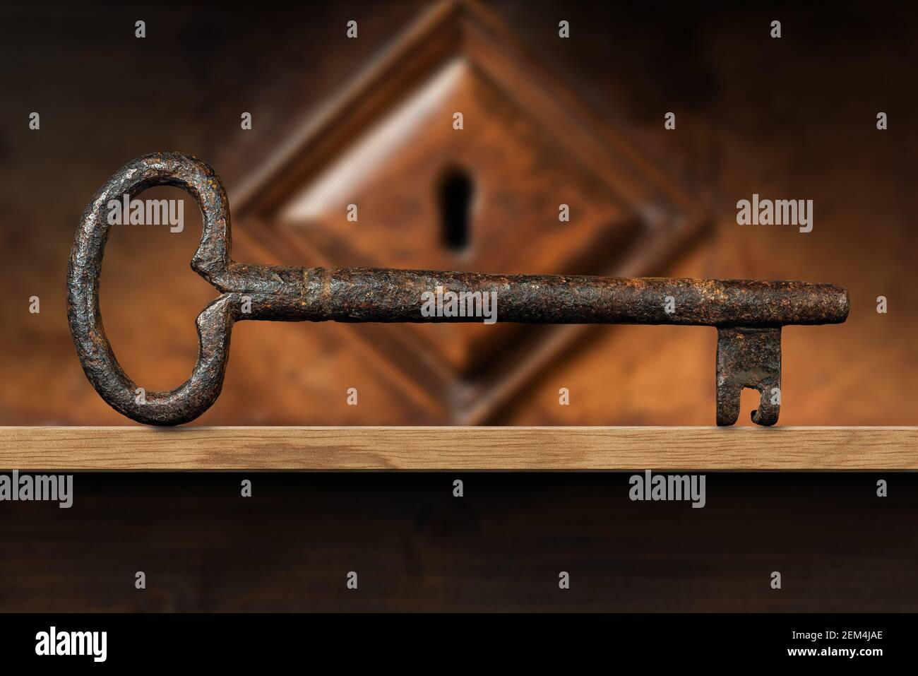 Extreme closeup of an old and vintage rusty key on a wooden shelf with a wood keyhole on background. Photography. Stock Photo