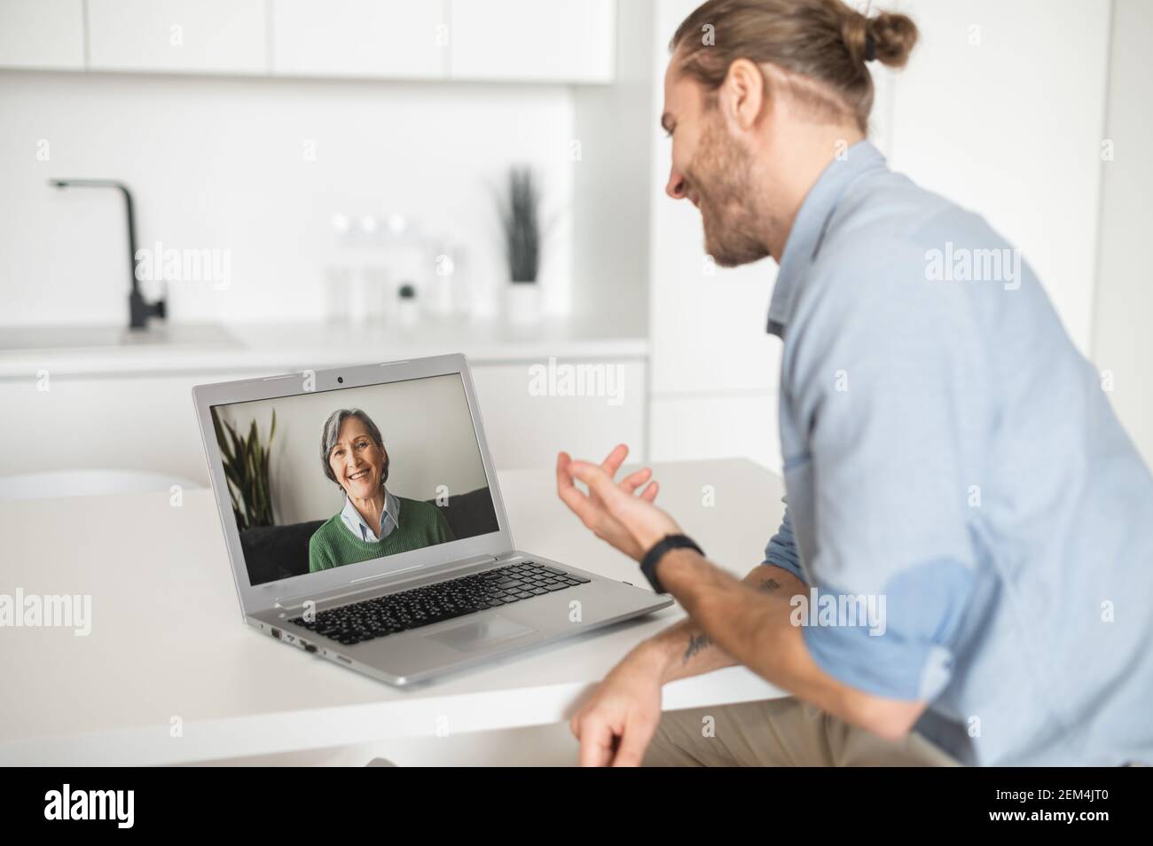 Nice and loving adult grandson talking to his elderly grandmother with gray hair and a sweet smile on video, telling about his life, family, work, successes and achievements, inviting her to visit Stock Photo