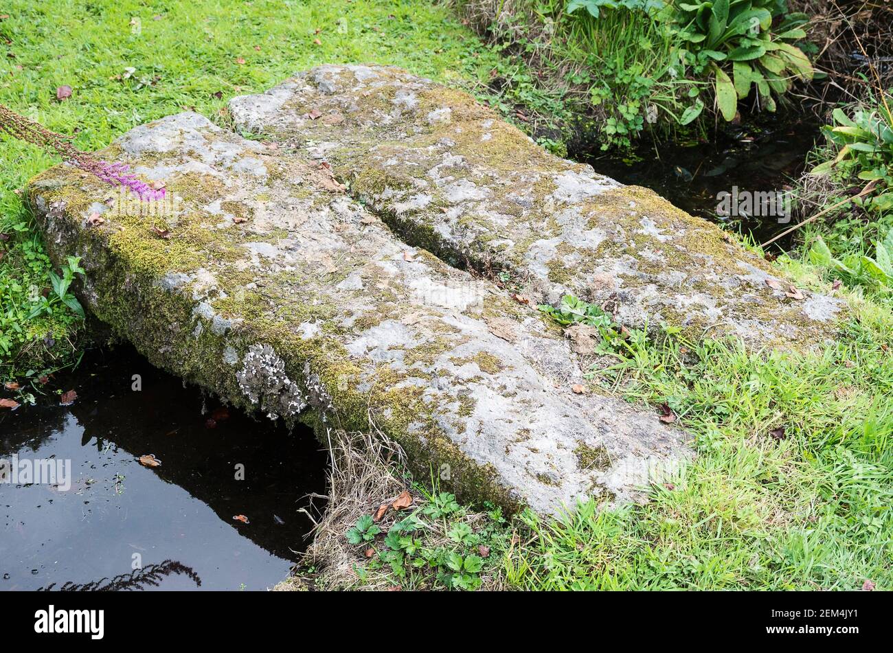 A simple natural stone footbridge crossing a small stream in an English garden UK Stock Photo