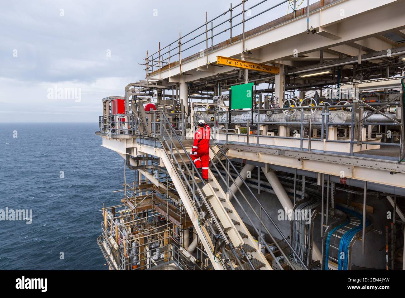 A worker walks up stairs on an offshore oil installation or rig Stock Photo