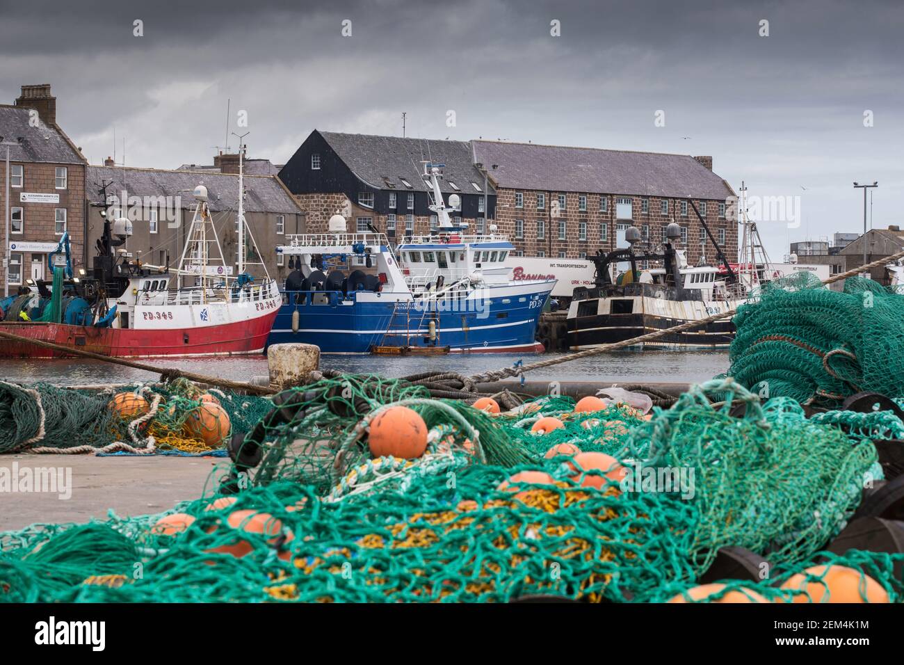 Fishing nets and gear in front of trawlers at Peterhead harbour in Aberdeenshire, Scotland, UK Stock Photo