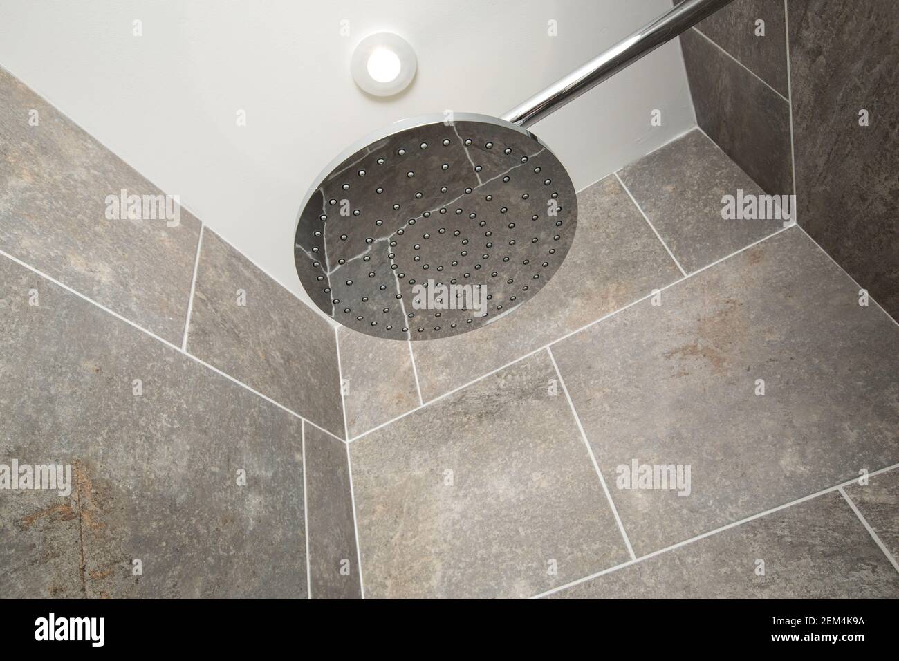 A large, modern shower head in a grey tiled shower Stock Photo