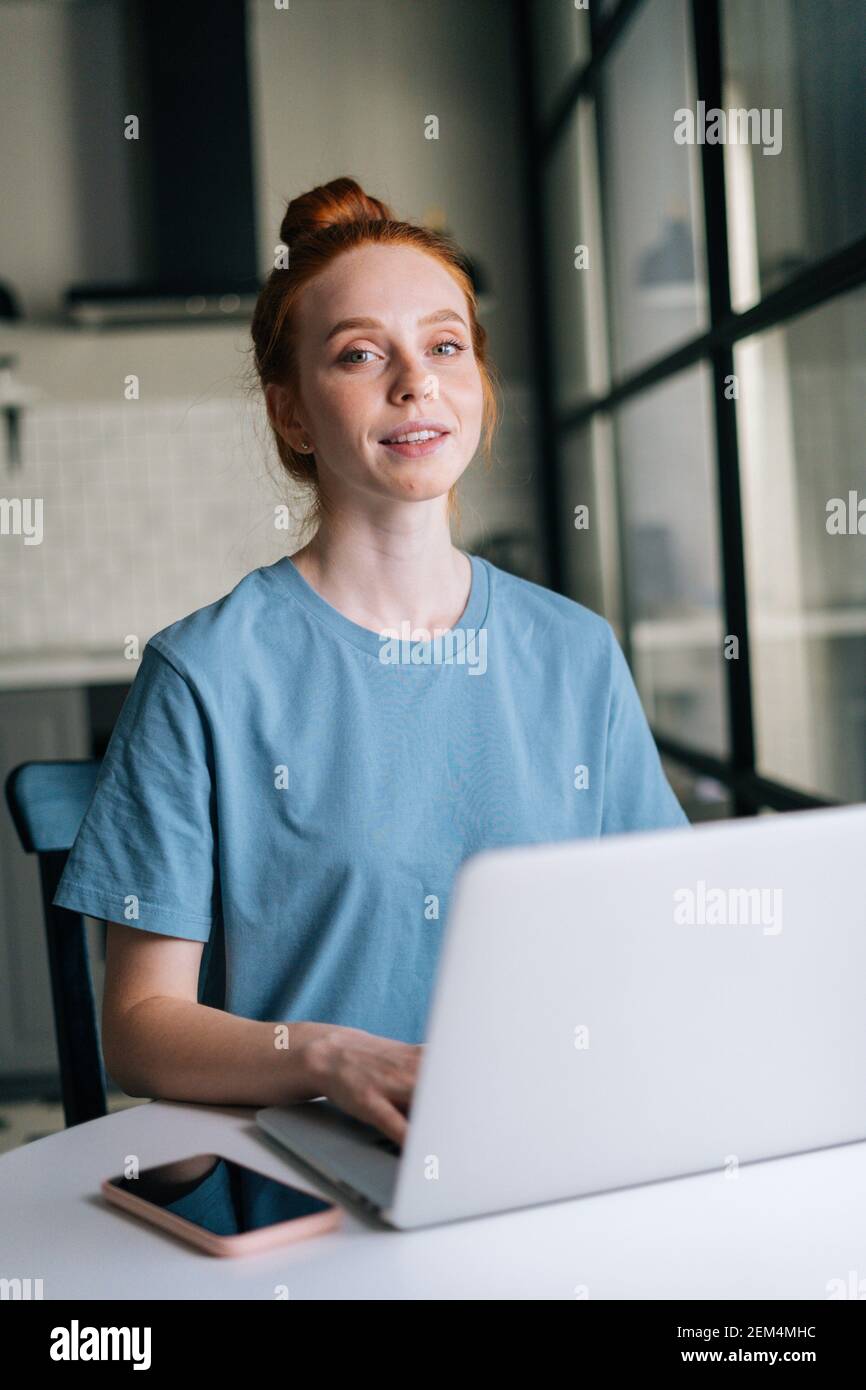 Portrait of cute redhead young woman working typing on laptop computer ...