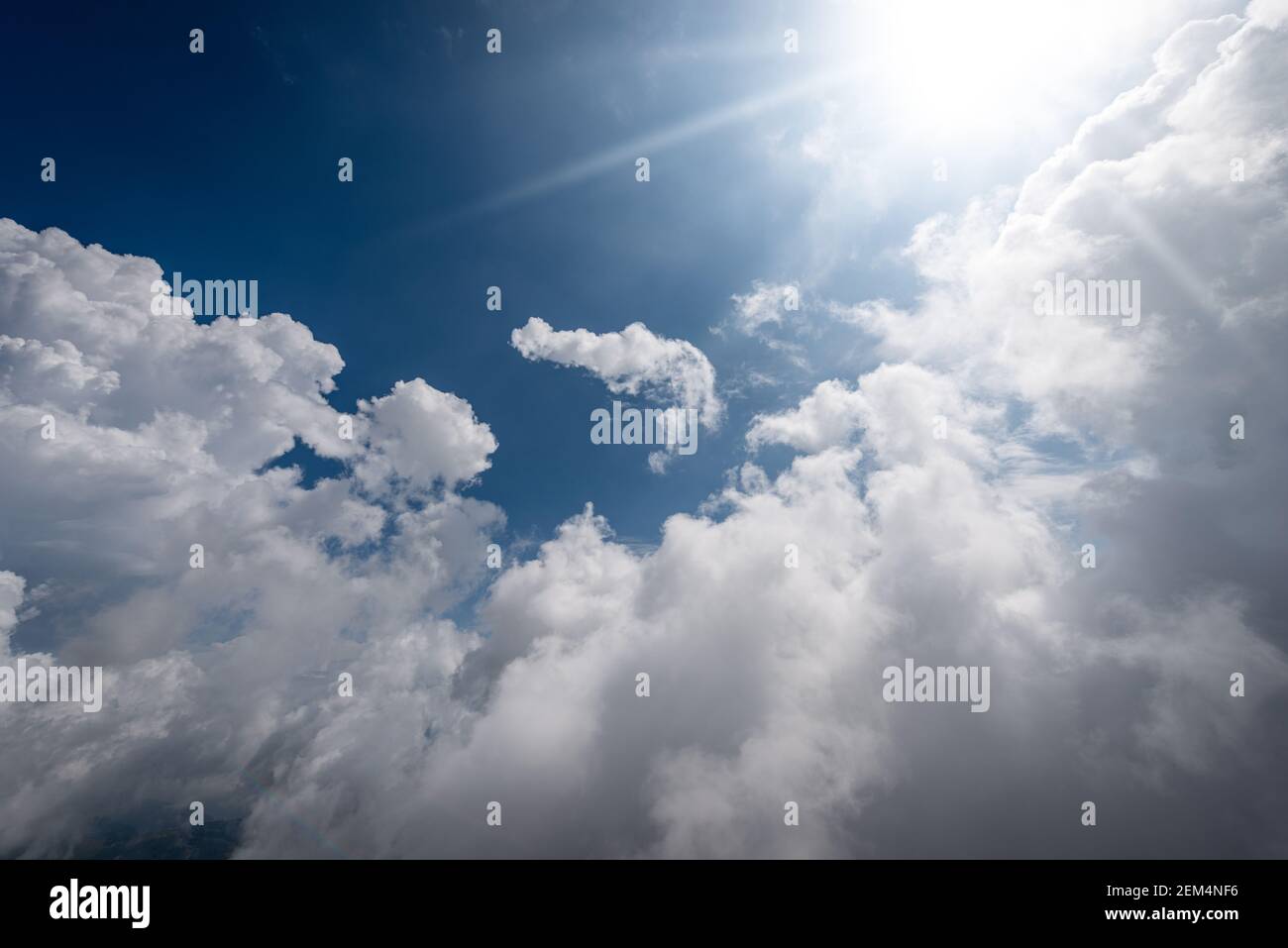 Beautiful blue sky with white cumulus clouds and sun rays, backlight ...