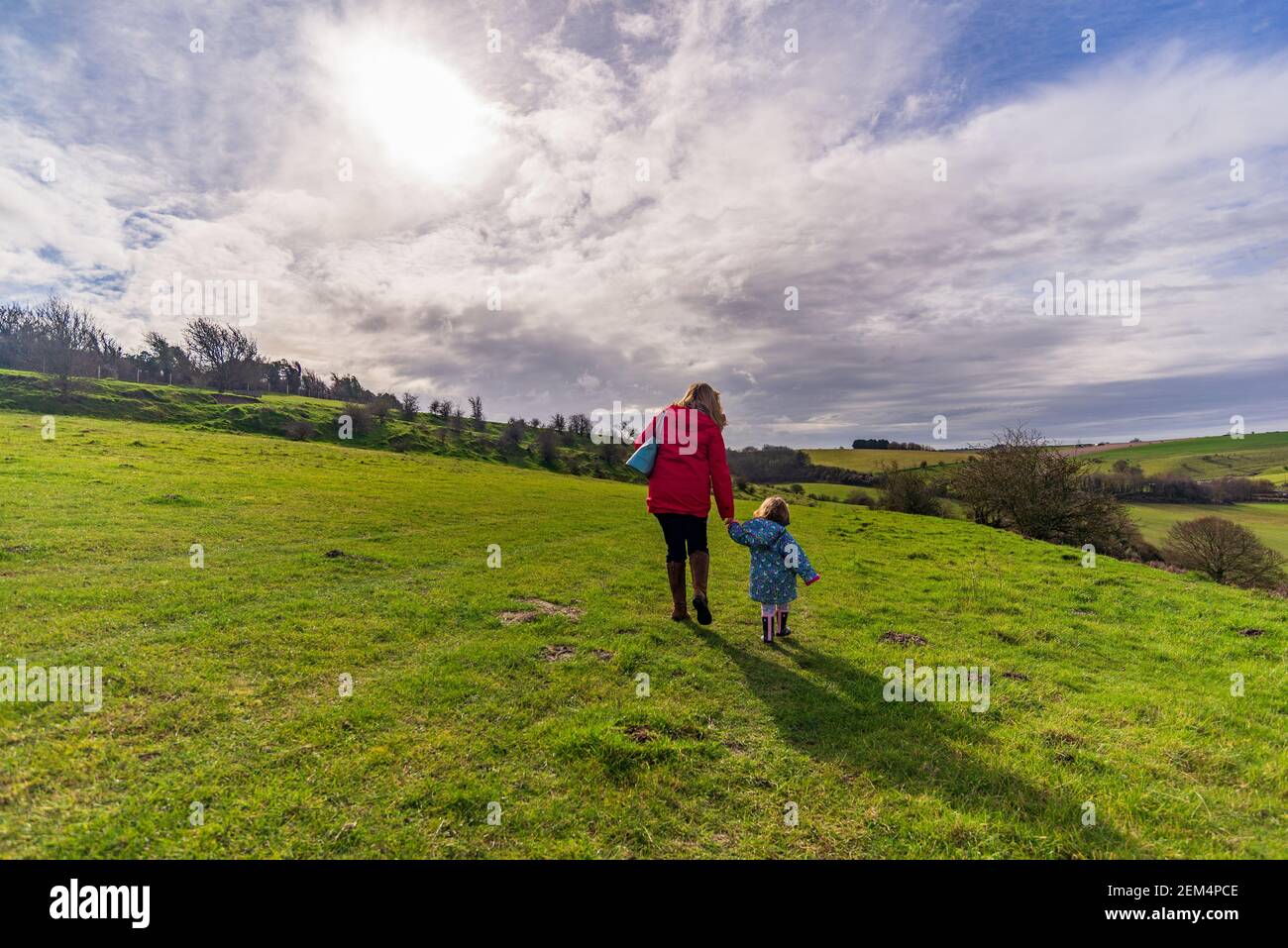 Coombe Bissett Down, Coombe Bissett, Salisbury, Wiltshire, UK, 24th February, 2021: Woman walking with small child in spring-like weather in the open countryside of the chalk downland nature reserve. Temperatures rose into the mid-teens, making it an unseasonably mild day. Credit: Paul Biggins/Alamy Live News Stock Photo