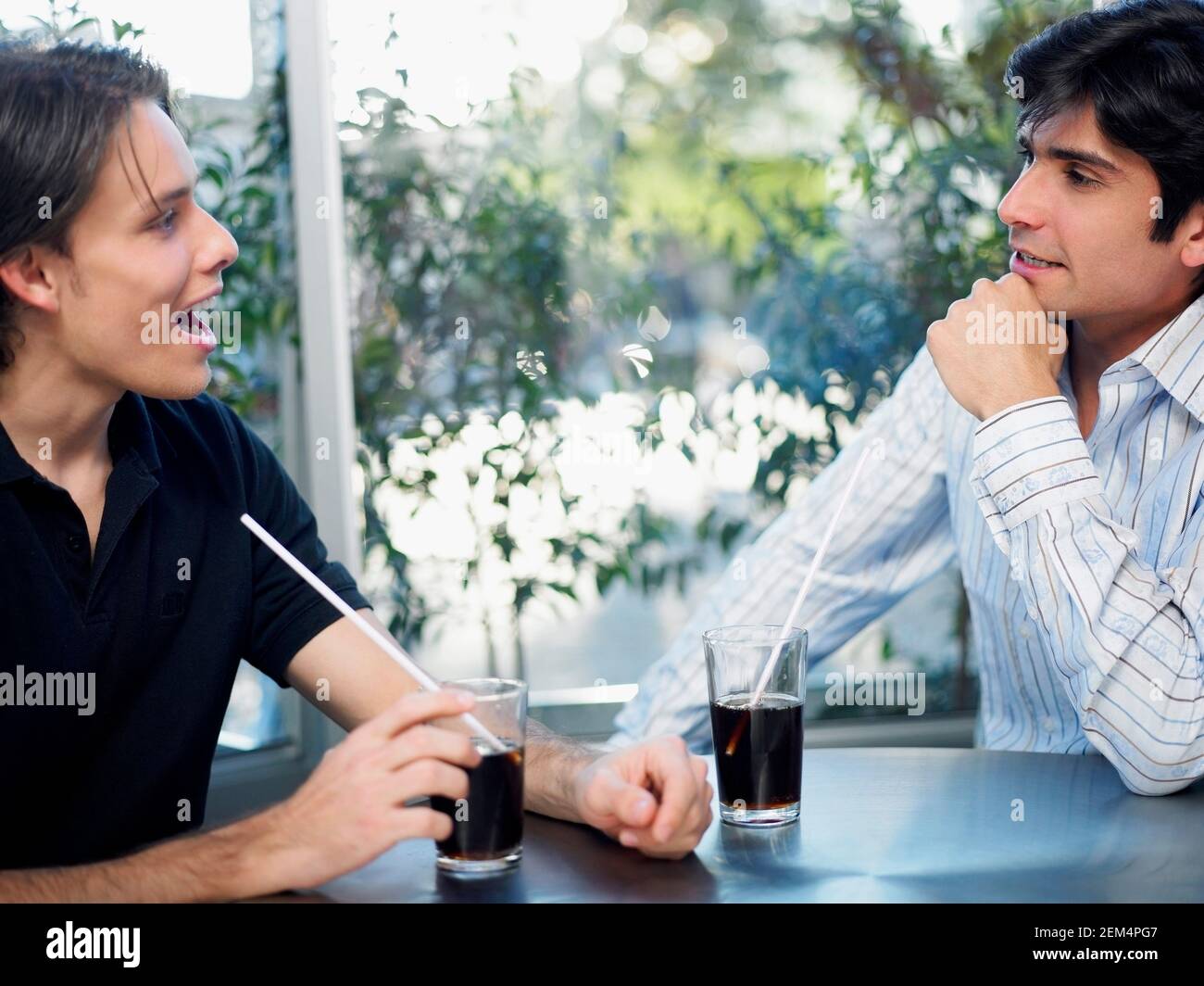 Close-up of a young man and a mid adult man sitting in a restaurant Stock Photo