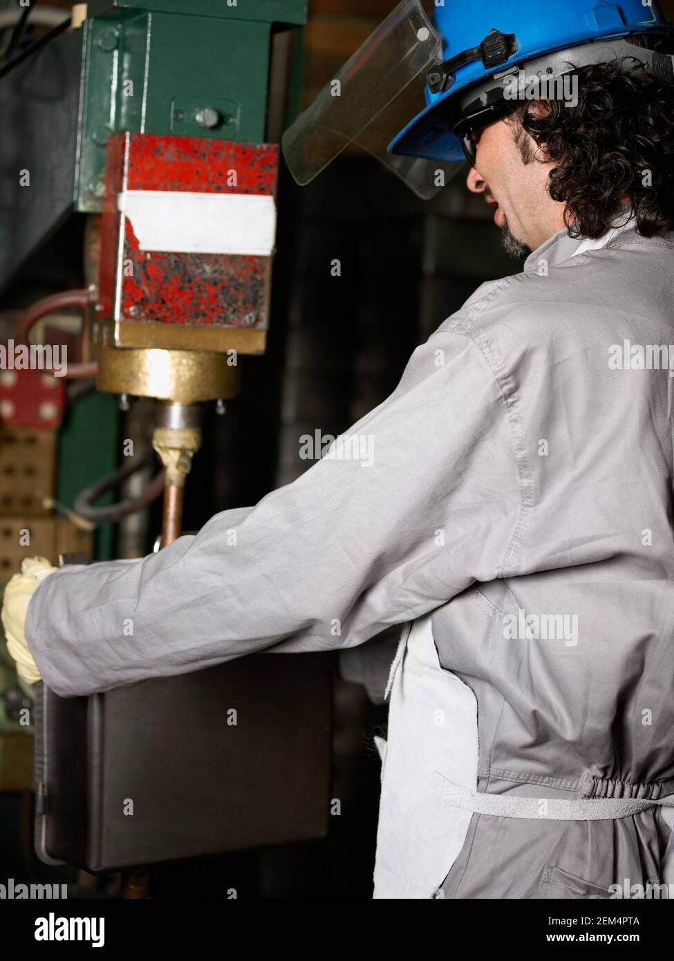 Side profile of a manual worker working on a spot welding machine Stock Photo