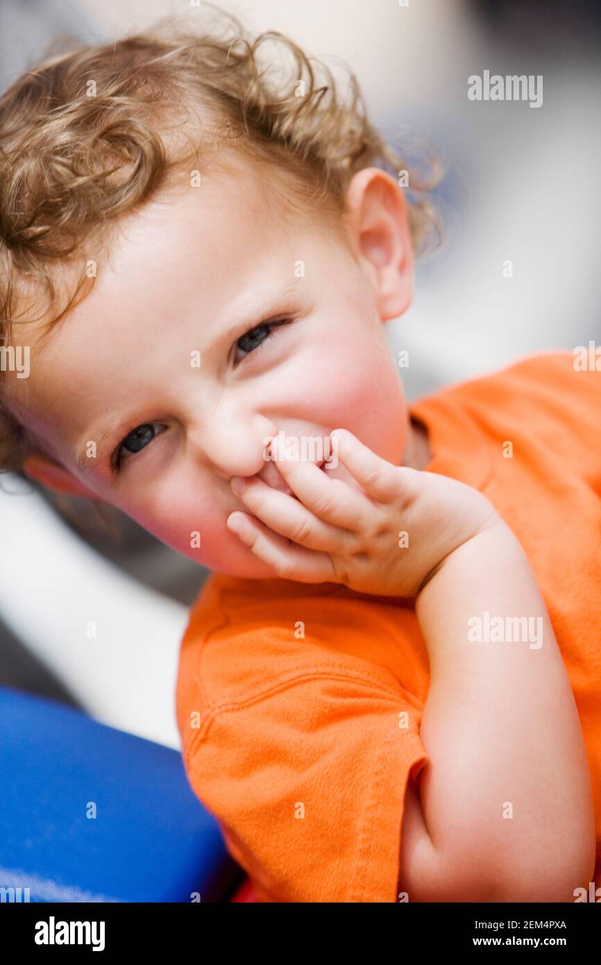 Portrait of a boy with his hand over his mouth Stock Photo
