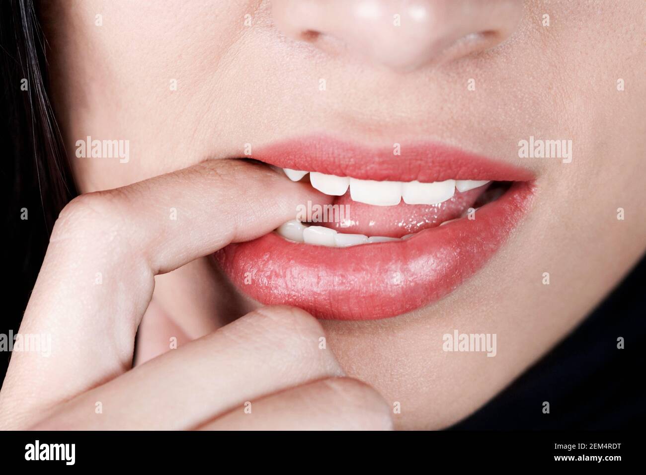 Close-up of a woman with her finger in her mouth Stock Photo