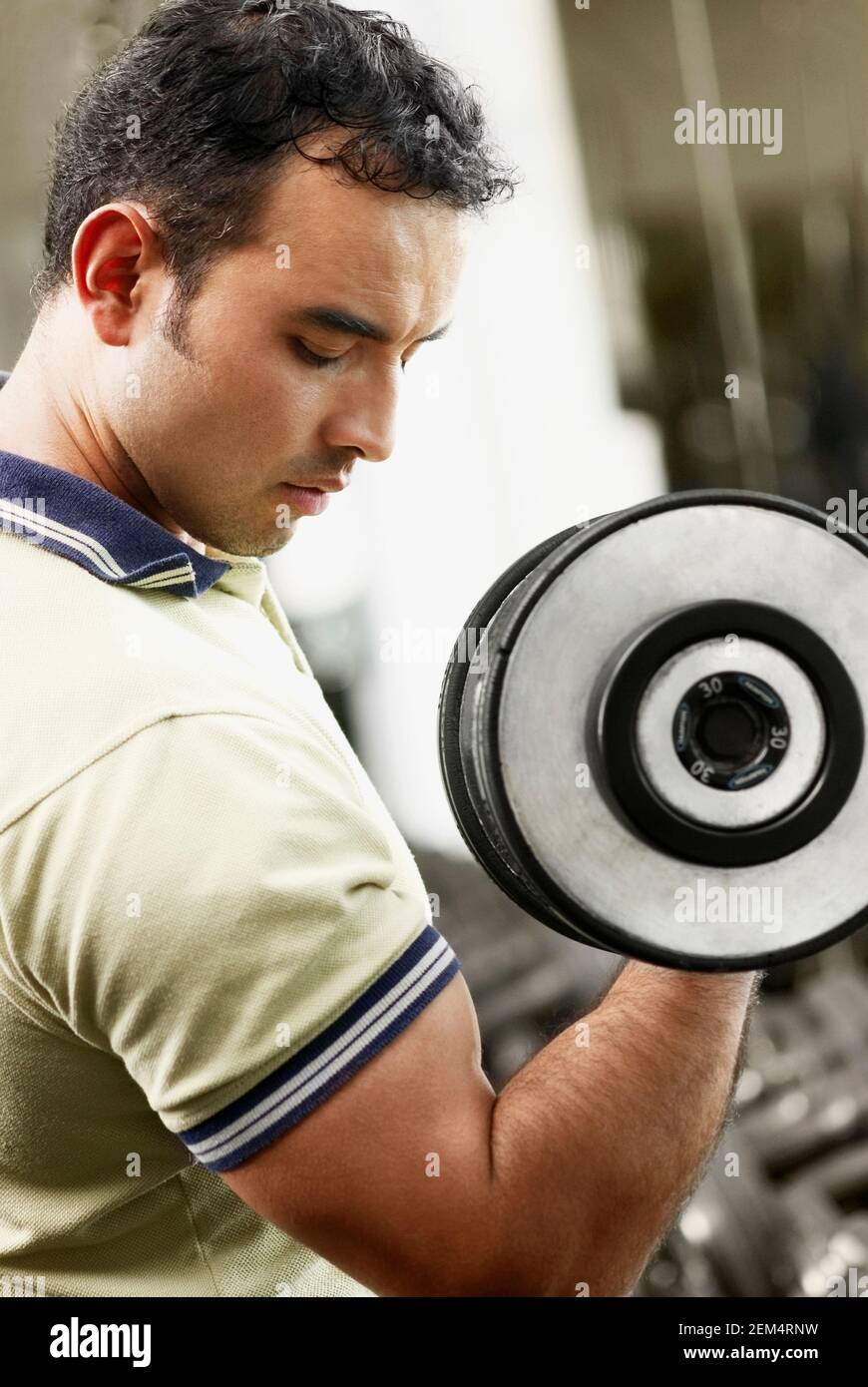 Side profile of a mid adult man exercising with a dumbbell Stock Photo