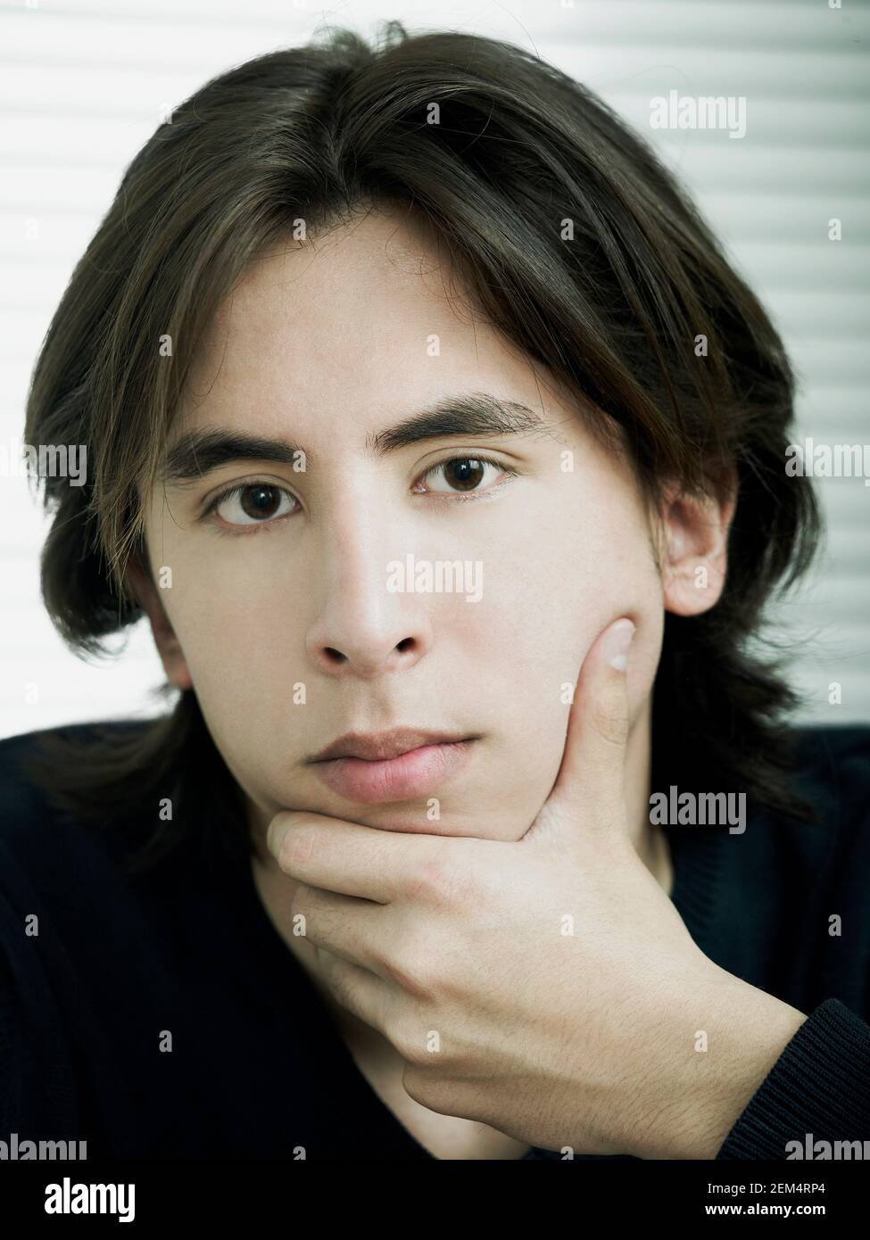 Portrait of a young man with his hand on his chin Stock Photo