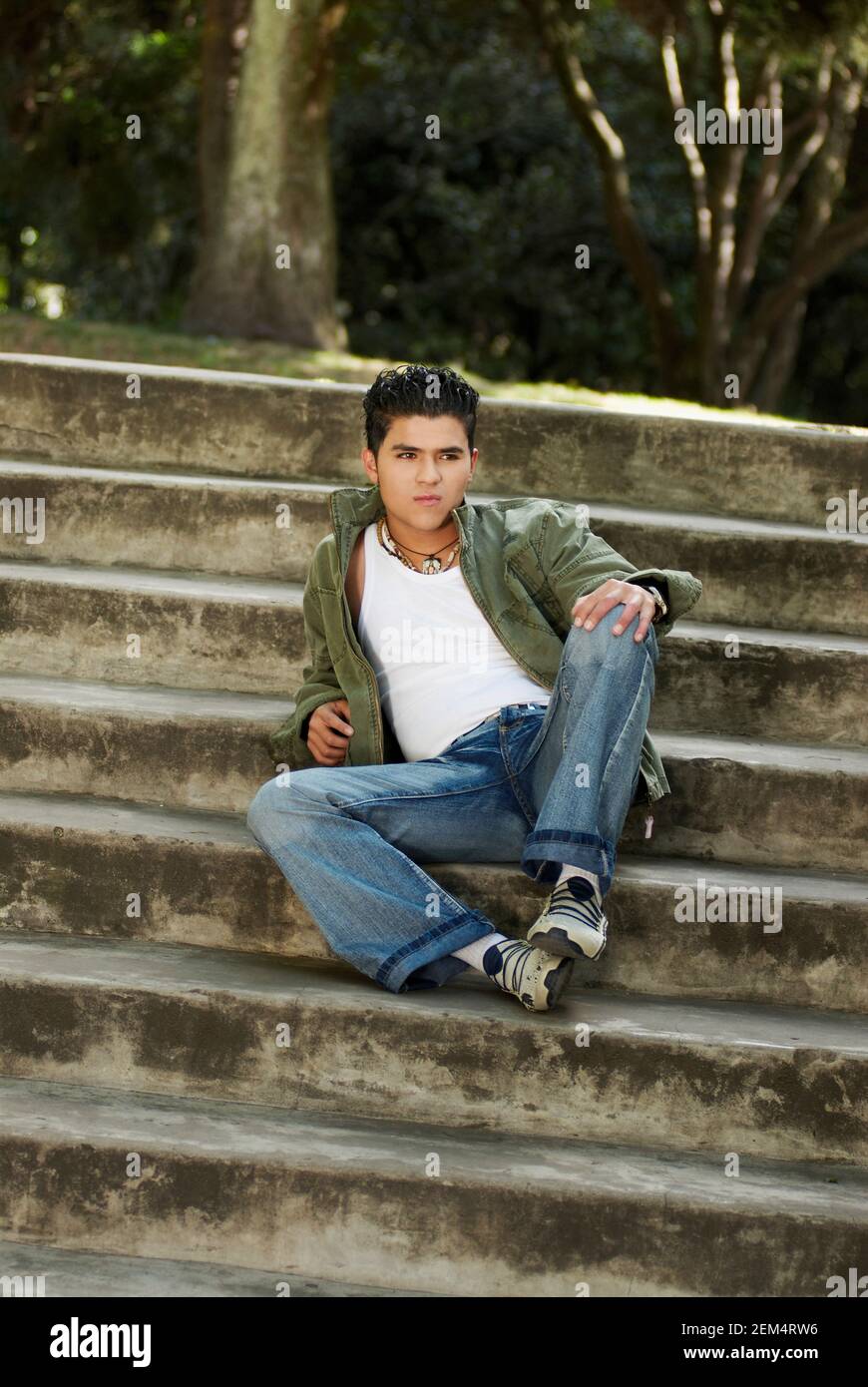 Mid adult man sitting on steps and looking away Stock Photo