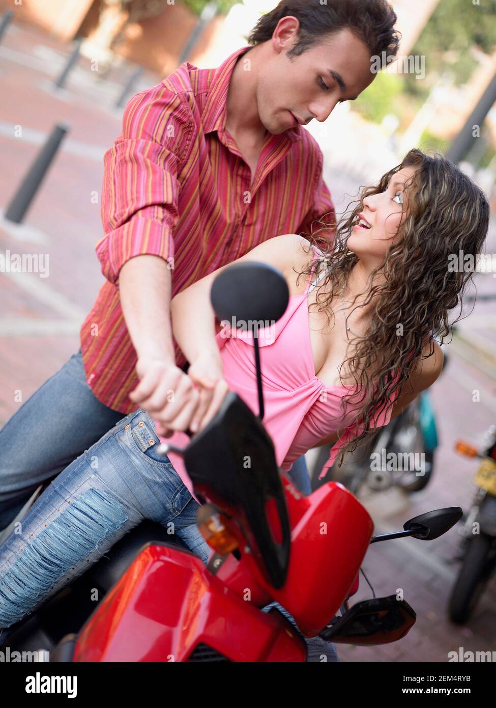Young man teaching a young woman how to drive a motor scooter Stock Photo