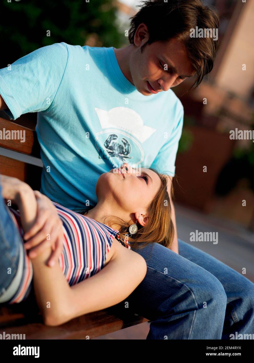 Close-up of a young woman lying on a park bench with her head on the lap of a young man Stock Photo